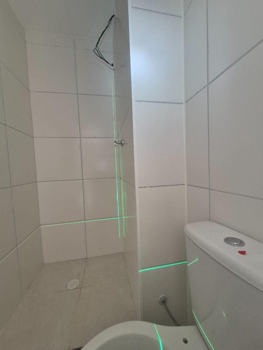 Linhas verdes do nível a laser projetadas nas paredes de um banheiro